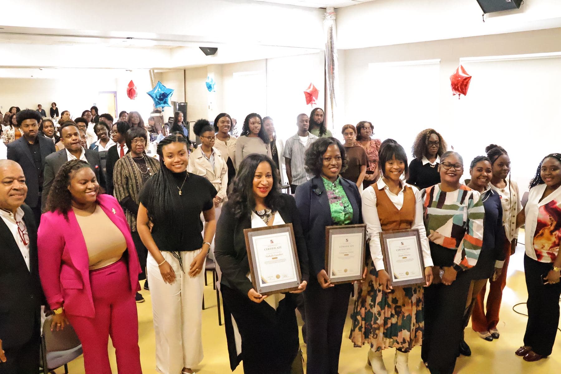 A group of speakers and students holding framed certificates